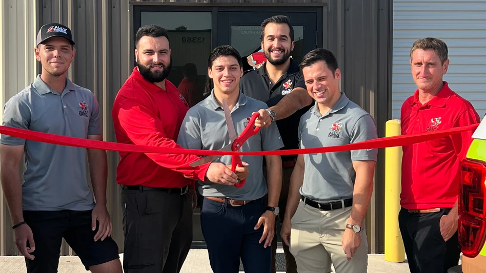 Photo of All U Need Pest Control employees cutting a ribbon in front of their new office.